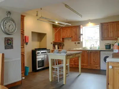 a kitchen with wooden cabinets and a table in it at Culpee House in Newton Stewart