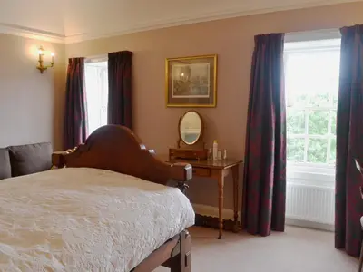 a bedroom with a bed and a mirror and windows at Culpee House in Newton Stewart