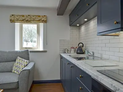 a kitchen with blue cabinets and a sink and a chair at The Dairy - Uk30867 in St Bees
