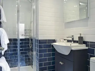 a blue and white bathroom with a sink and a shower at The Dairy - Uk30867 in St Bees