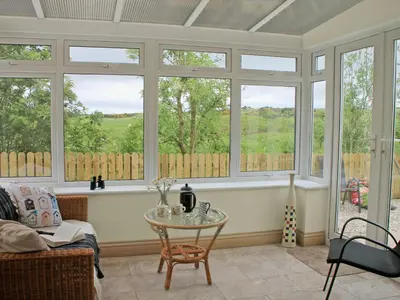 a living room with windows and a table at Swallows in Girthon