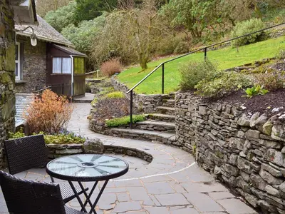 a patio with a table and a stone wall at The Coach House - Uk30813 in Braithwaite