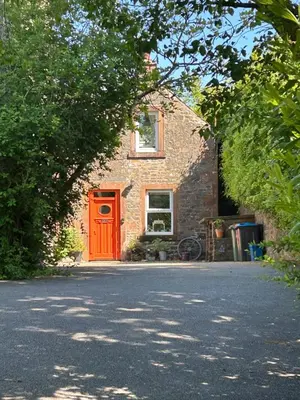 a brick house with a red door on a street at Fox Cottage in Moffat