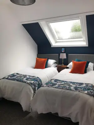 two beds in a room with a window at Fox Cottage in Moffat