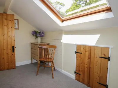 a skylight in a attic room with a chair and a wooden cabinet at Acorn Cottage in Coniston