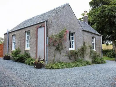 a small brick building with a door and flowers on it at Rose Blair Lodge - Uk31045 in Portpatrick