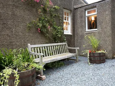 a wooden bench in front of a building with plants at Rose Blair Lodge - Uk31045 in Portpatrick