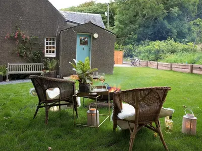a house with two chairs and a table in the grass at Rose Blair Lodge - Uk31045 in Portpatrick