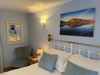 a bedroom with a bed and a chair and a mirror at Lakeland Snug in Keswick