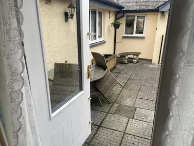 an open door to a patio with a table and chairs at Lakeland Snug in Keswick