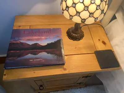 a book sitting on a table next to a lamp at Lakeland Snug in Keswick
