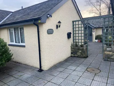 a white house with a gate and a driveway at Lakeland Snug in Keswick