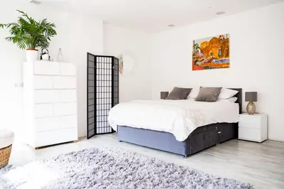 a white bedroom with a large bed and a rug at Tholt-y-Will B&B in Sulby