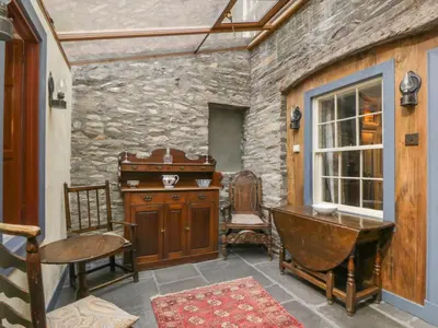 a room with a stone wall and a table and a desk at The Precinct House in Newton Stewart