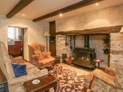 a living room with a stone fireplace and a couch and chair at The Pend in Newton Stewart