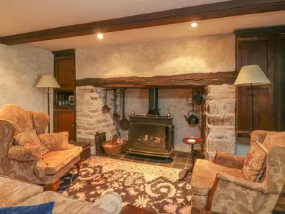 a living room with a fireplace and a stone wall at The Pend in Newton Stewart