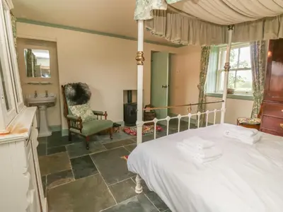 a bedroom with a bed and a chair and a sink at Faldarroch Farm in Newton Stewart