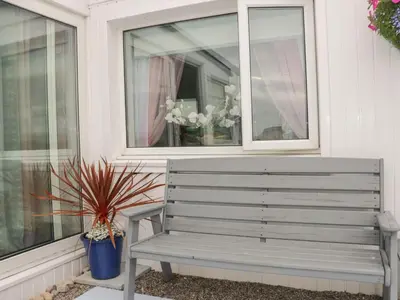 a gray bench next to a window with a potted plant at Sandpiper in Dumfries