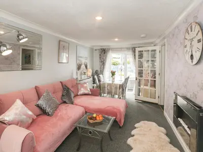 a living room with a pink couch and a table at Sandpiper in Dumfries