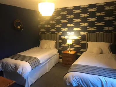 a hotel room with two beds and a wall with a wallpaper at The Stables in Castle Douglas
