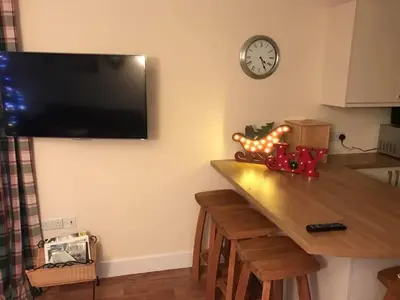 a kitchen with a table and a clock on a wall at The Stables in Castle Douglas