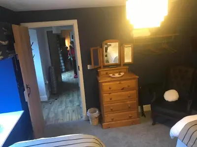 a bedroom with a dresser with a mirror and a chair at The Stables in Castle Douglas
