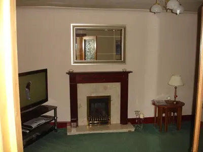 a living room with a fireplace and a television at RoSE COTTAGE THREE BEDROOM HOUSE WITH PARKING Christmas Special in Carsphairn
