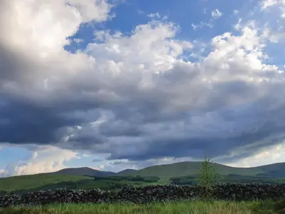 a cloudy sky with a stone wall in a field at Lavender Cottage with Parking and Beautiful Views Christmas Special in Carsphairn