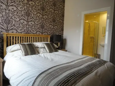 a bedroom with a large bed with white sheets at Arden House Hotel in Kirkcudbright