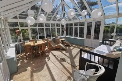 a conservatory with a table and chairs in a room with windows at Cosy, Coastal Retreat with a Large Garden in Monreith