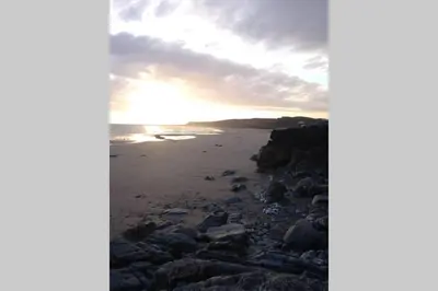 a view of a beach at sunset at Cosy, Coastal Retreat with a Large Garden in Monreith
