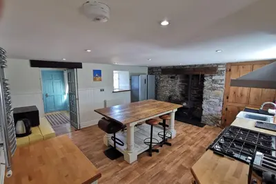 a kitchen with a wooden table and a stove at Cosy, Coastal Retreat with a Large Garden in Monreith