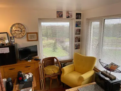 a living room with a yellow chair and a television at Jacquie's B&B -Dumfries-Room with a view in Dumfries