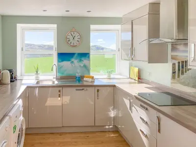 a kitchen with a sink and a clock on the wall at Ardstinchar Mews in Ballantrae