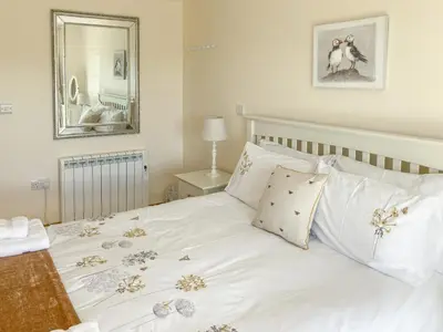 a bedroom with a white bed with flowers on it at Ardstinchar Mews in Ballantrae