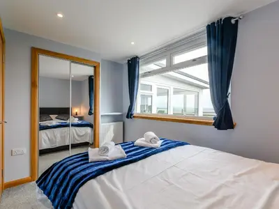 a bedroom with a large bed with towels on it at Sand View in Mainsriddle