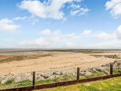 a fence in front of a sandy beach at Sand View in Mainsriddle