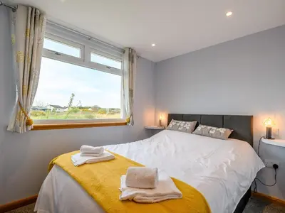 a bedroom with a large white bed with a window at Sand View in Mainsriddle