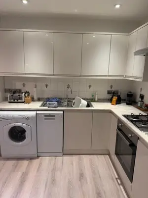 a kitchen with white cabinets and a washing machine at The Haven Keswick - Spacious Central Apartment in Keswick