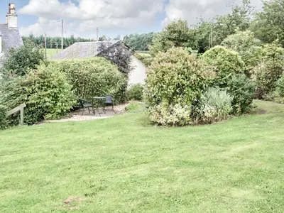 a garden with a table and chairs in a yard at The Grooms Cottage in Mauchline