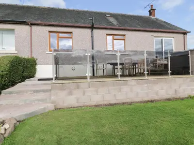 a house with a patio with a table and chairs at Tarnacrye in Annan
