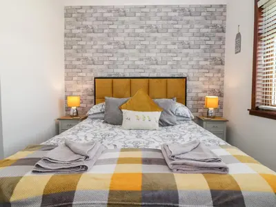 a bedroom with a large bed with two lamps at Tarnacrye in Annan