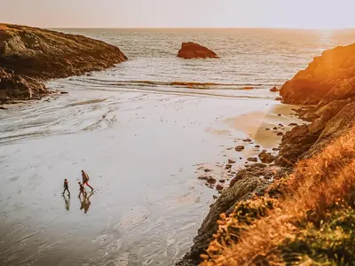 two people walking on a beach near the ocean at Coachman in Enoch