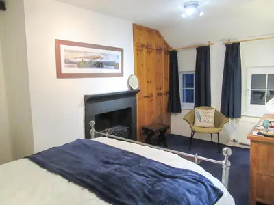 a bedroom with a bed with a fireplace and a chair at Garden Cottage in Threlkeld