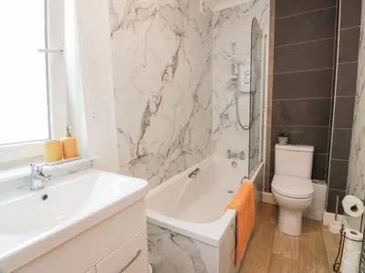 a bathroom with a white tub and a toilet and a sink at Simply Suite in Castle Douglas
