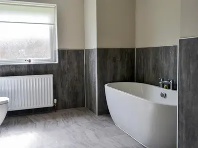 a bathroom with a large white tub and a window at Dinduff Lodge in Challoch
