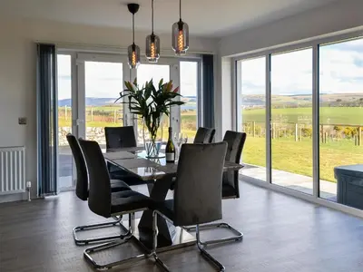 a dining room with a table and chairs and windows at Dinduff Lodge in Challoch