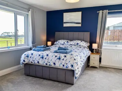 a bedroom with a bed with blue walls and windows at Dinduff Lodge in Challoch