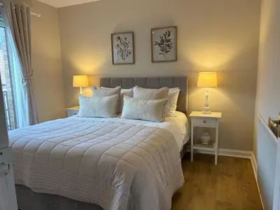 a bedroom with a large bed with two lamps at Kincraig Apartment in Ayr