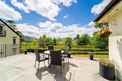 a patio with a table and chairs and a fence at Borrowdale View in Keswick